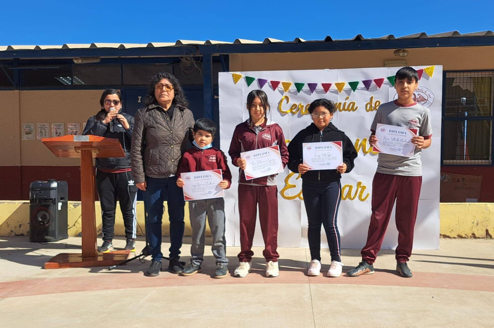 Alumnos premiados exhiben diplomas junto al docente en la ceremonia de convivencia escolar en Paposo.
