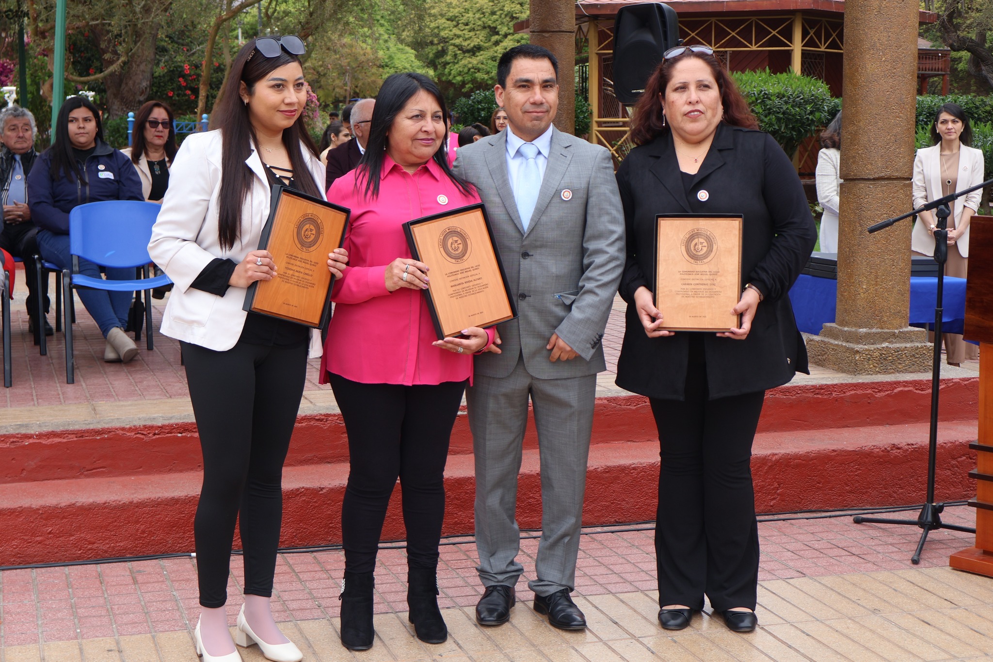 Tres apoderadas reconocidas junto al equipo directivo muestran sus placas durante el aniversario 86.