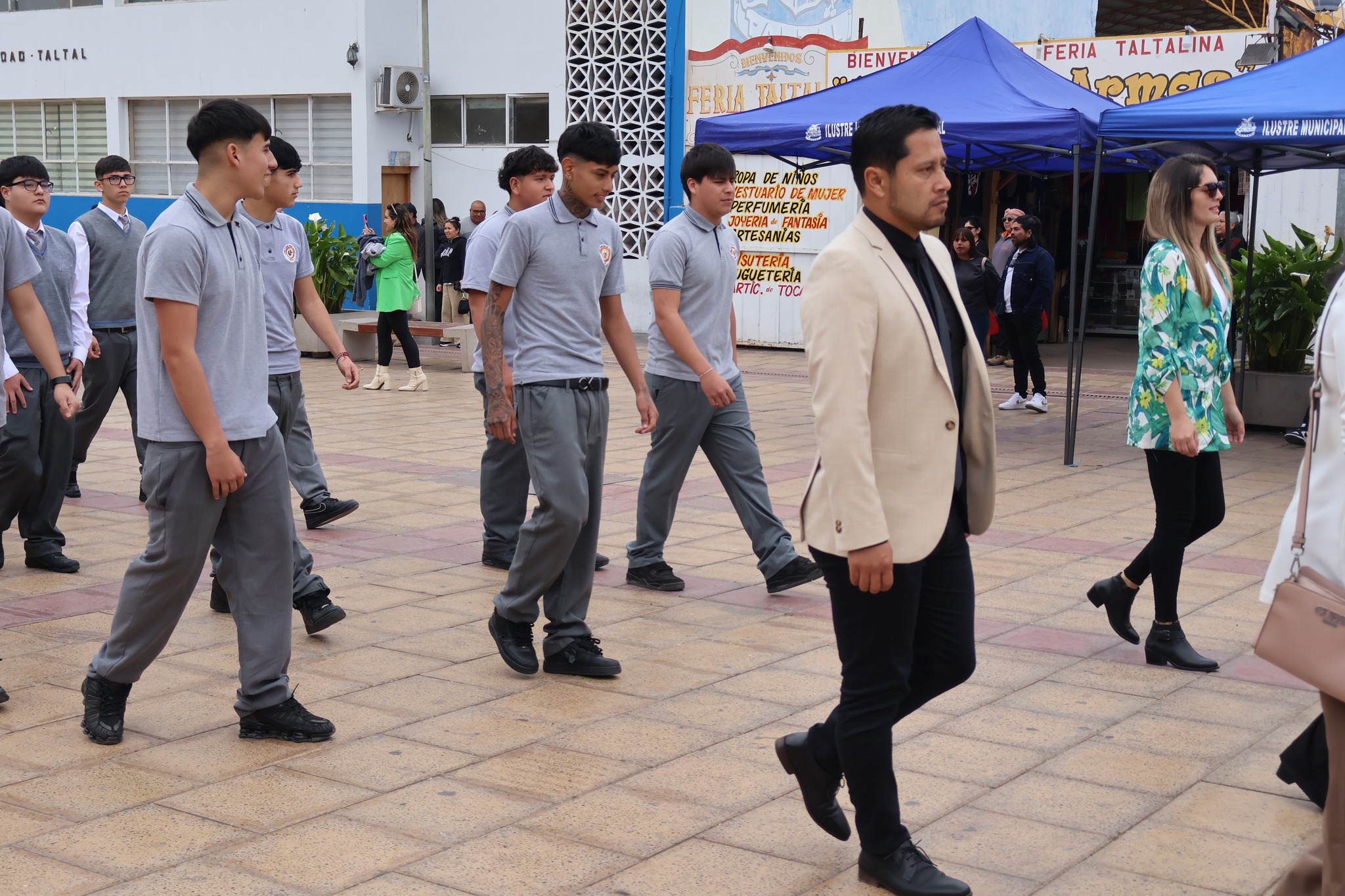 Curso de varones con polera institucional desfila junto a profesorado por la Plaza Arturo Prat.