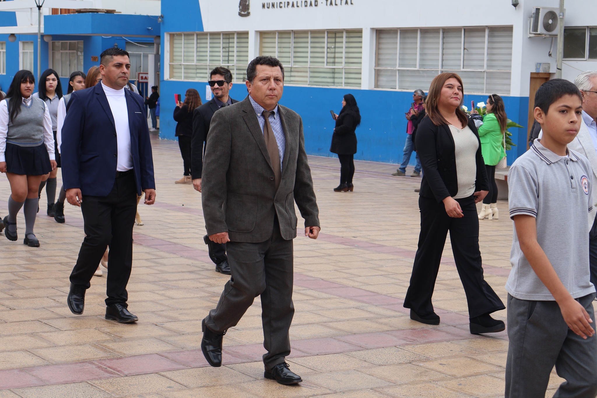 Equipo de docentes y asistentes de la educación marcha tras el estandarte institucional.