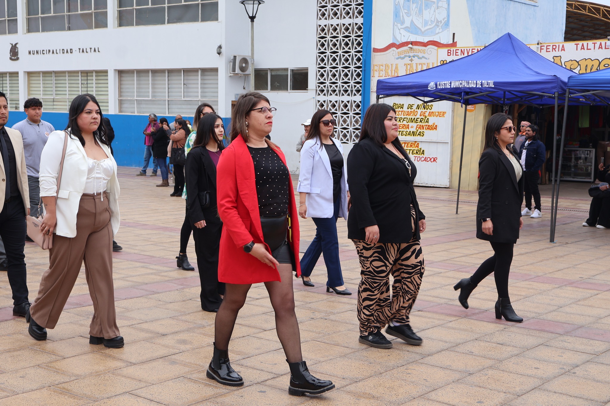 Funcionarias del establecimiento marchan; destaca una integrante con abrigo rojo al frente.