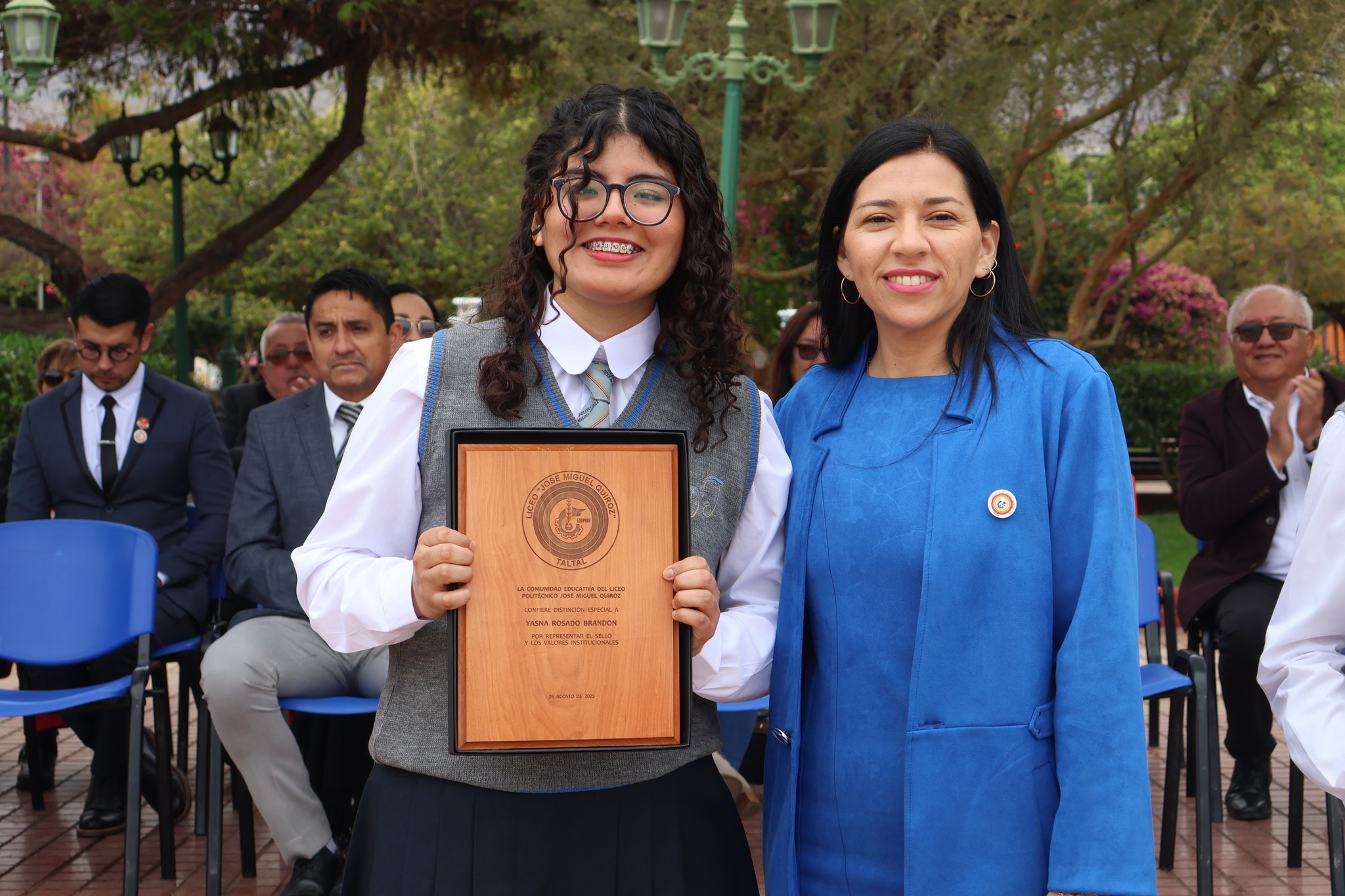 Alumna destacada es premiada por representación y valores del liceo; posa con directiva ante el público.