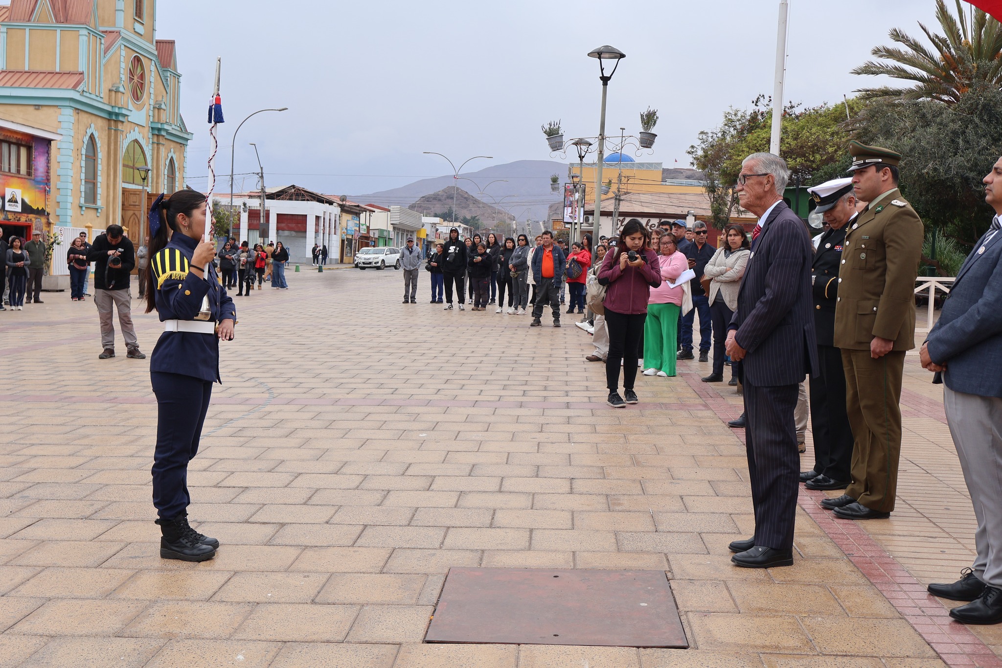 Bastonera de la banda escolar rinde honores frente a autoridades comunales en la Plaza Arturo Prat.