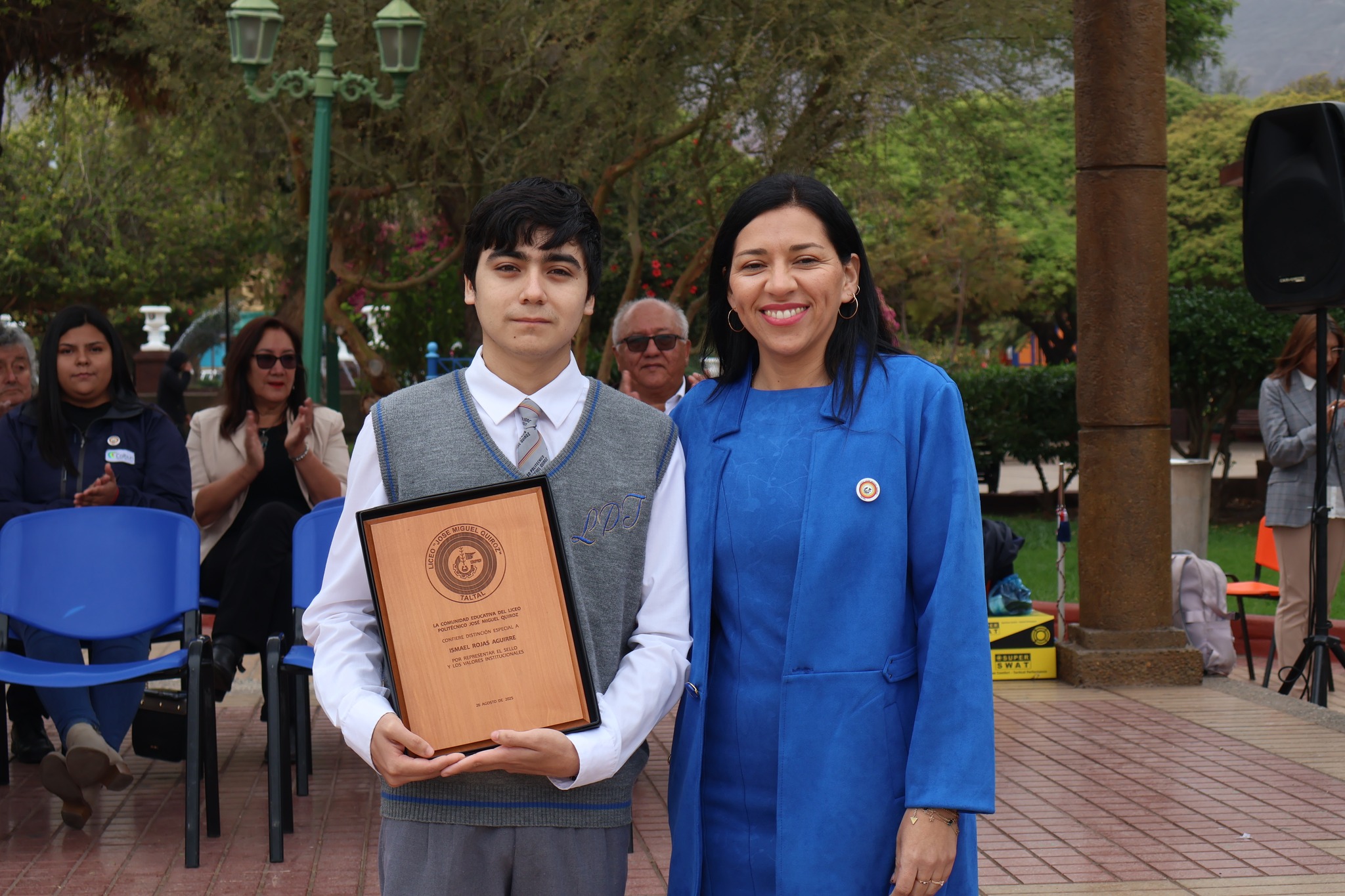 Estudiante reconocido con placa de madera durante la conmemoración de los 86 años del Liceo José Miguel Quiroz.