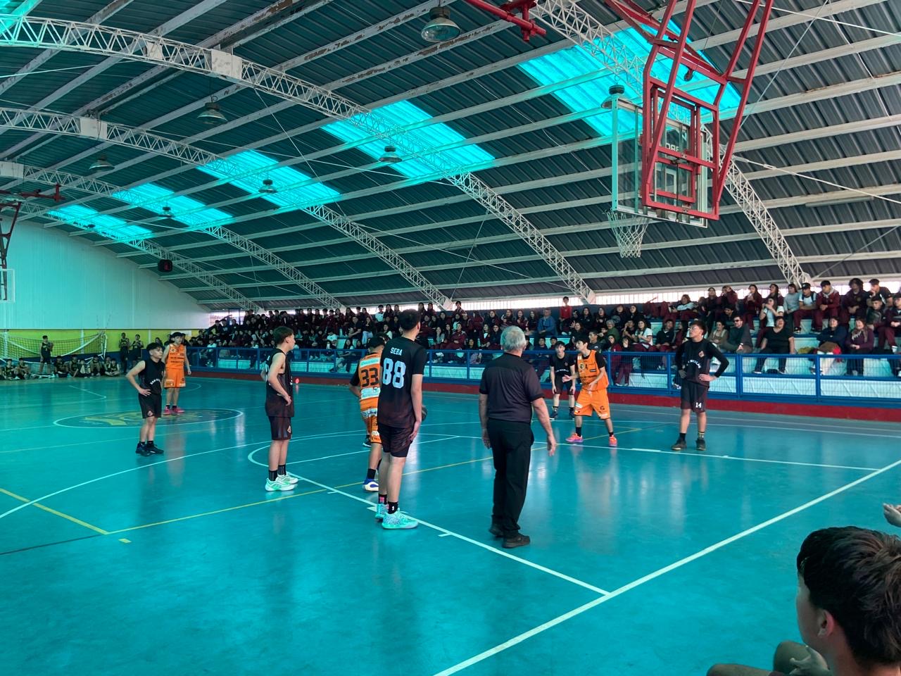 Acción de la final masculina en el Estadio Techado de Taltal entre Colegio San Luis y Liceo C-21, con tribunas repletas.
