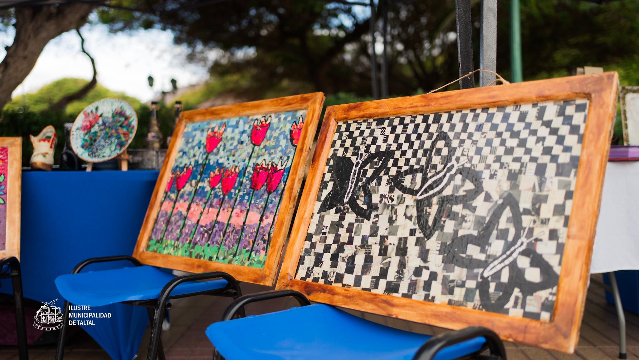 Cuadros artesanales en exposicion, uno con mariposas sobre patron ajedrezado.