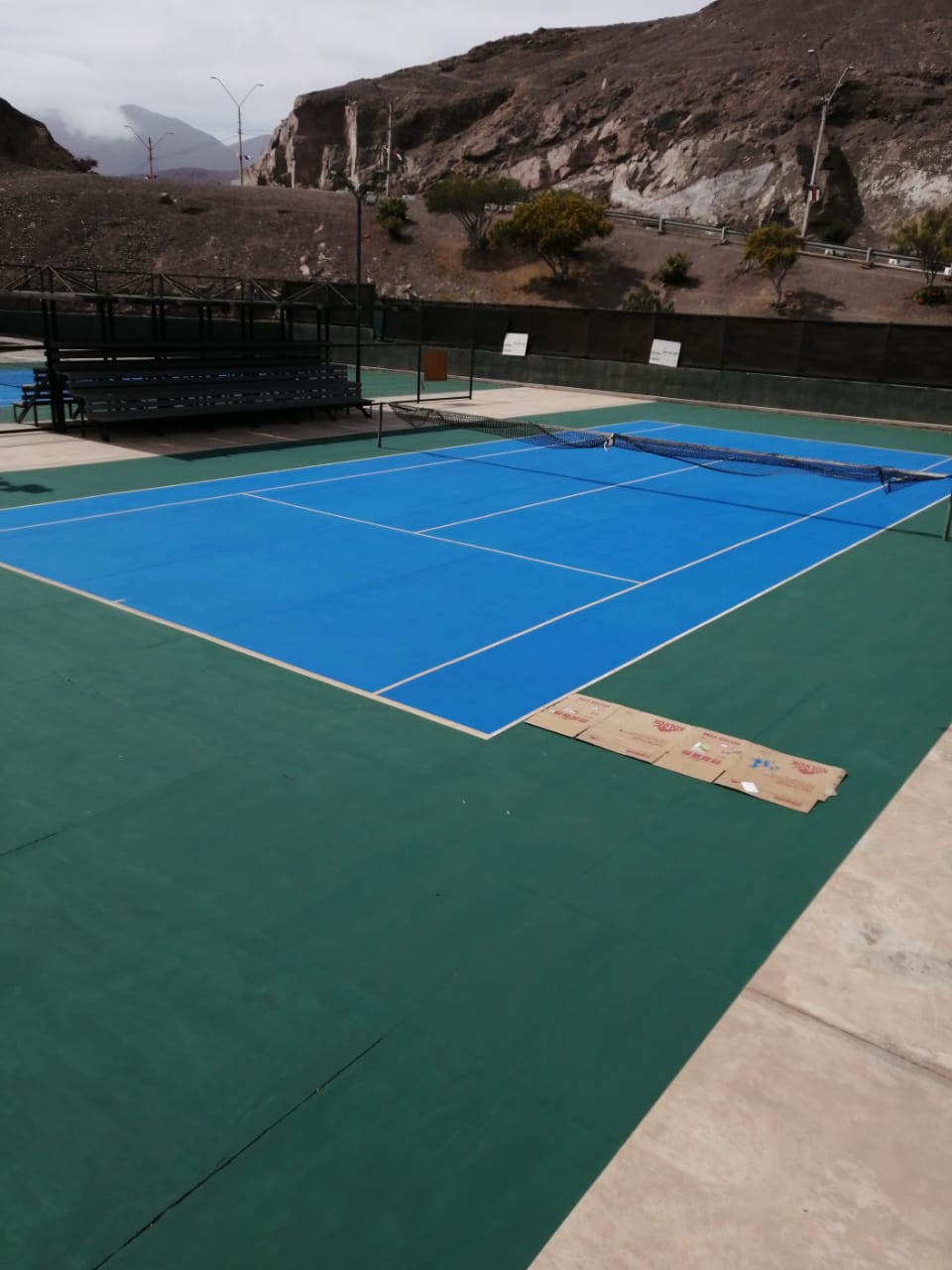 Cancha de tenis con superficie recien pintada en tono azules.