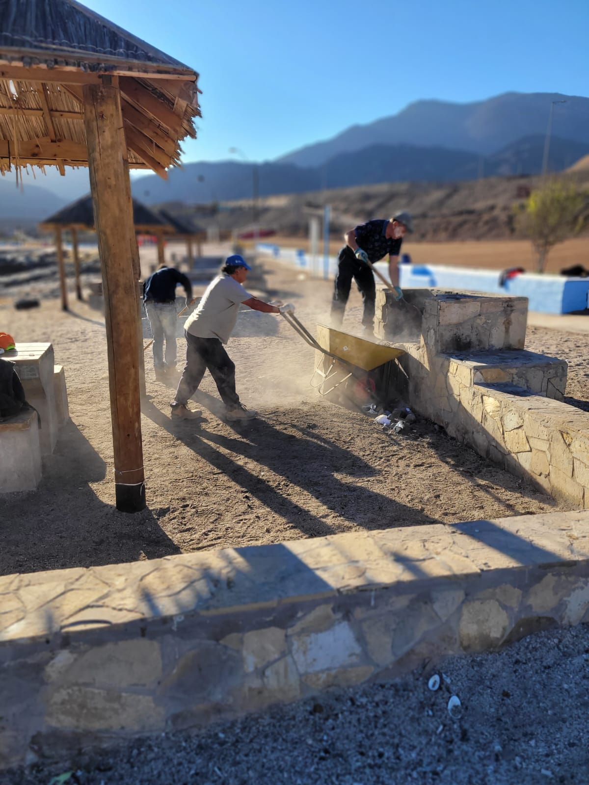 Trabajadores retiran residuos y arena desde la parrilla de un quincho durante operativo de limpieza municipal