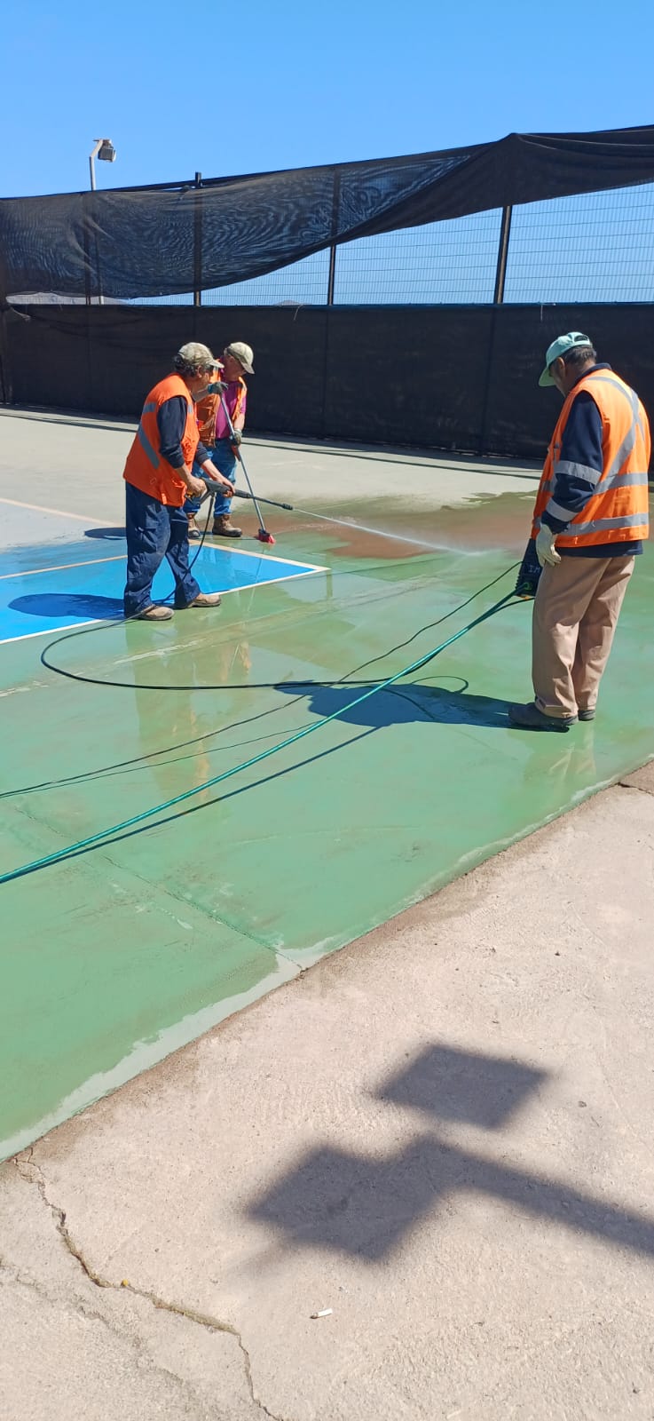 Trabajadores aplicando agua a presión sobre el sector verde