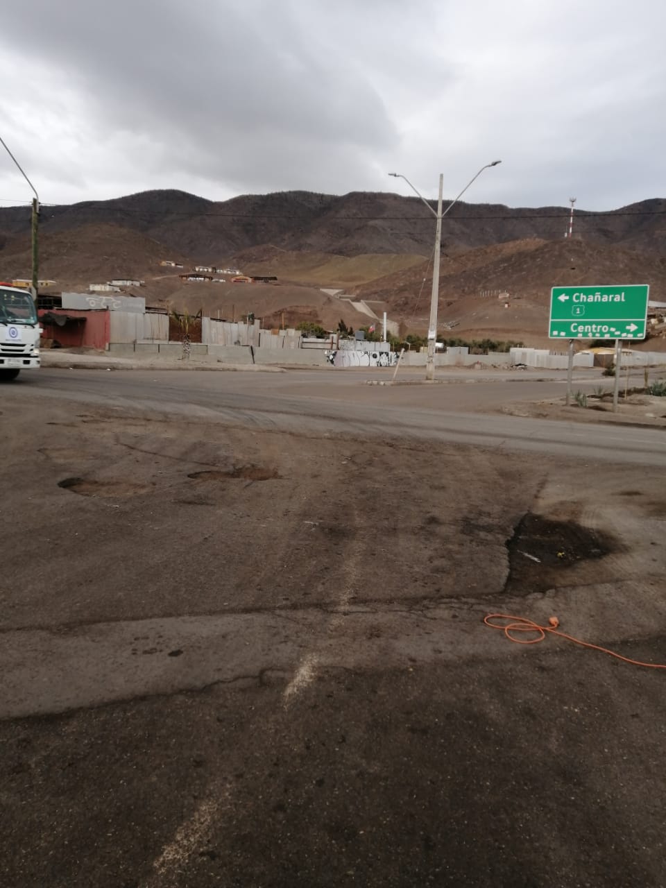 Panorámica del acceso sur de Taltal con baches visibles y señal hacia Chañaral y Centro, antes de la reparación.