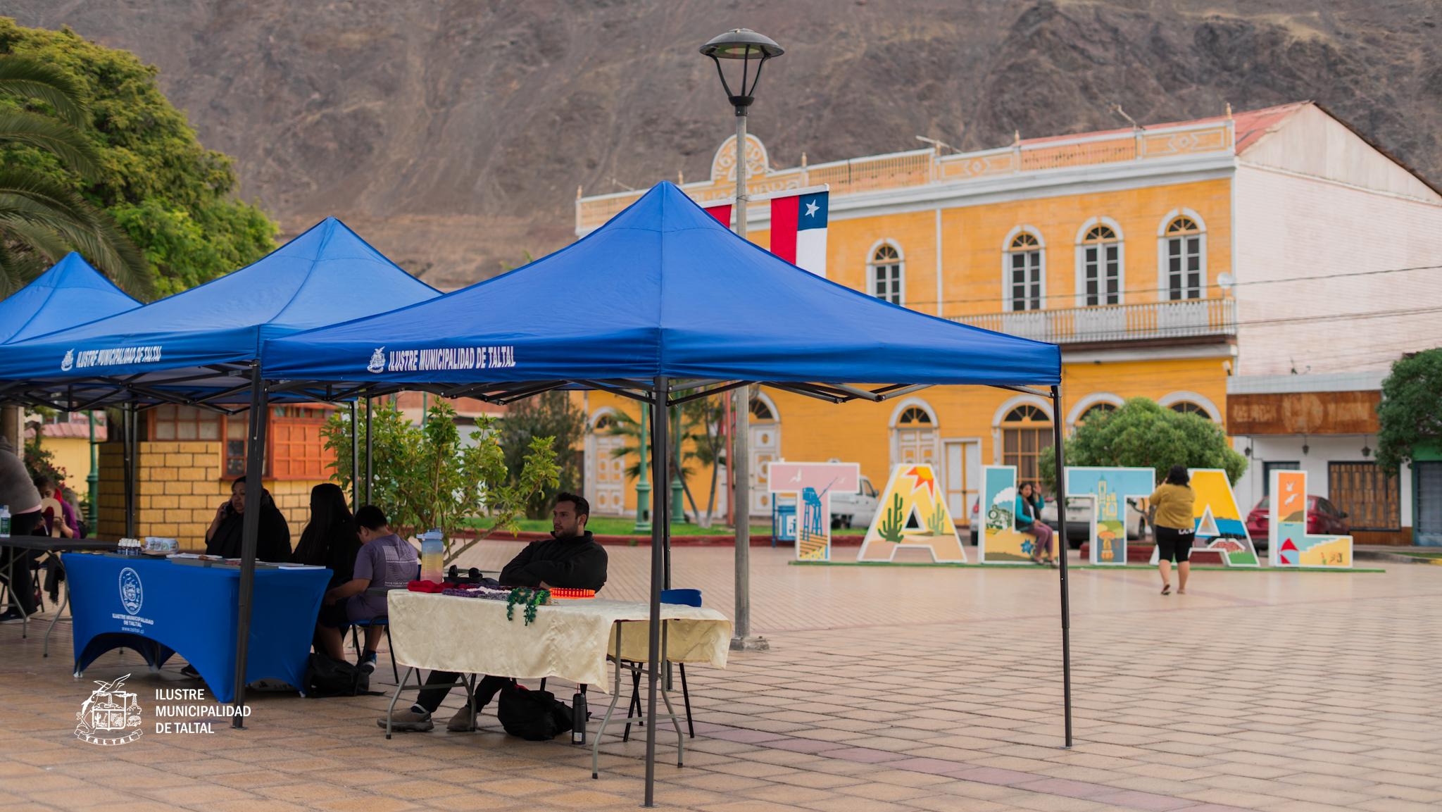 Carpas azules del municipio en Plaza Prat con letras TALTAL al fondo.