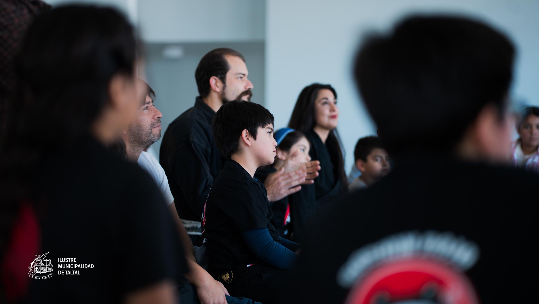 Jóvenes participantes sonríen y comparten con instructores durante la jornada de artes marciales en Taltal.