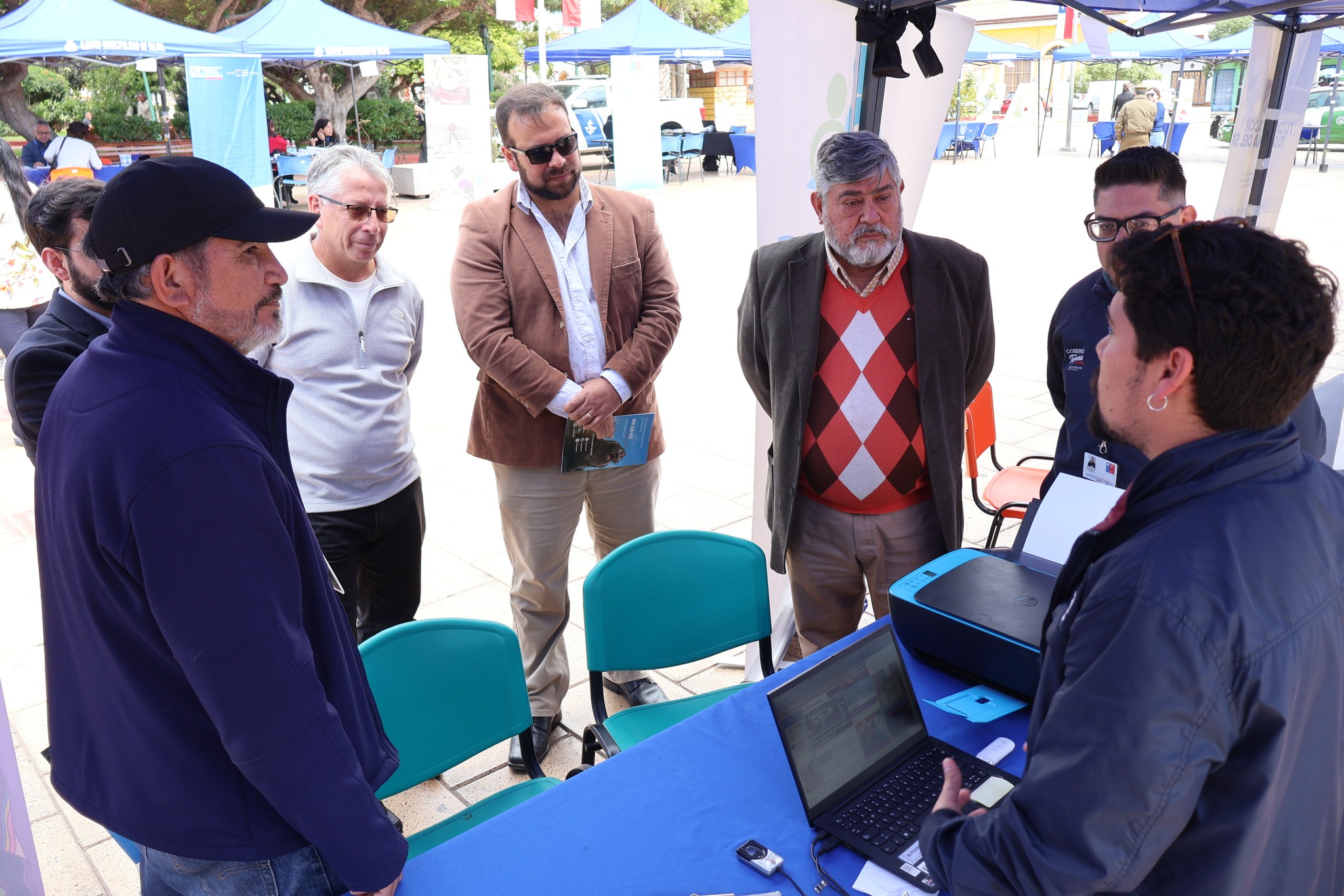 Autoridades conversan con funcionario en módulo con computador y servicios en línea durante Gobierno en Terreno.
