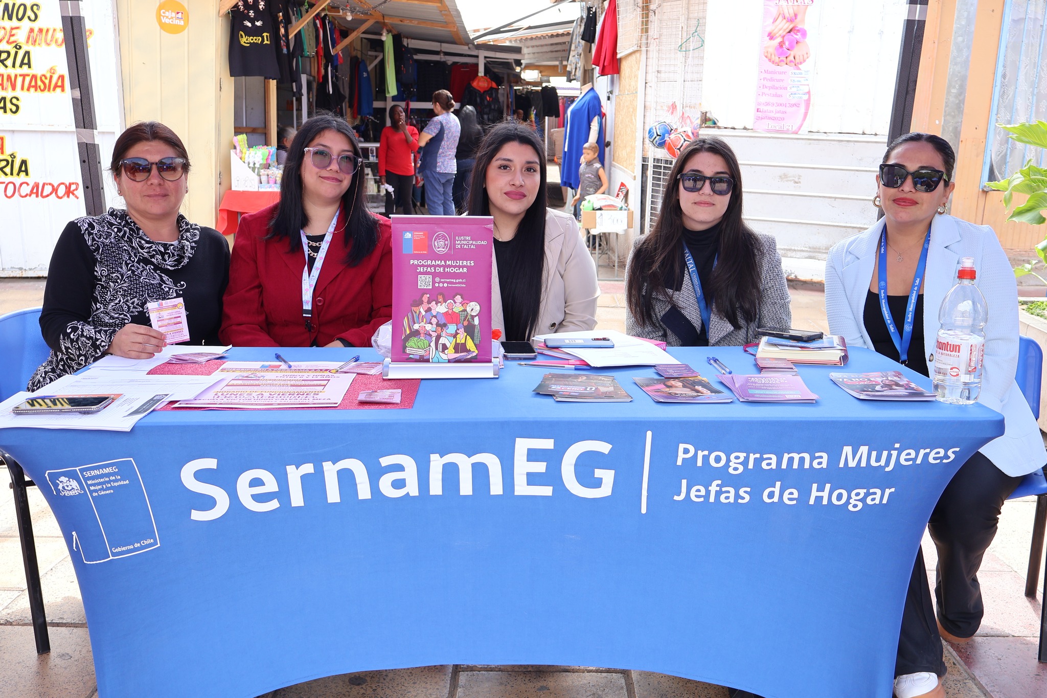 Equipo del programa Mujeres Jefas de Hogar de SernamEG atendiendo en su módulo de la feria en Plaza Prat