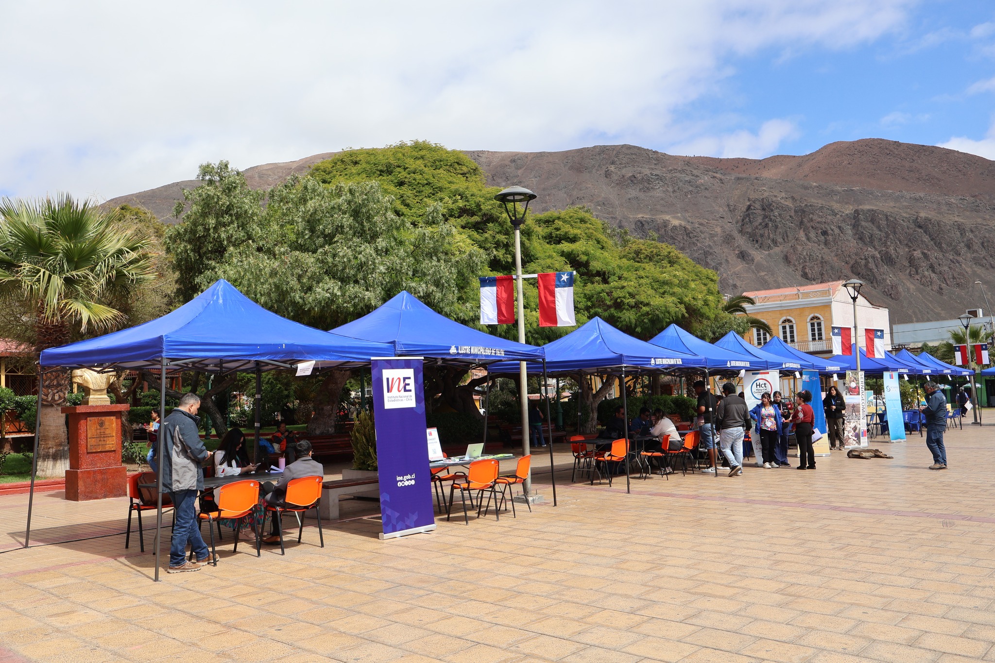 Panorámica de la feria Gobierno en Terreno en Plaza Prat de Taltal con carpas azules y banderas de Chile.