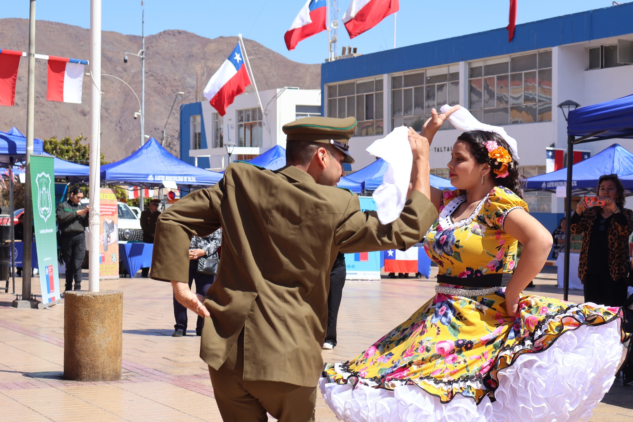 Carabinero y bailarina con vestido de huasa interpretan cueca en la Plaza de Taltal durante la Fonda Preventiva de Fiestas Patrias.
