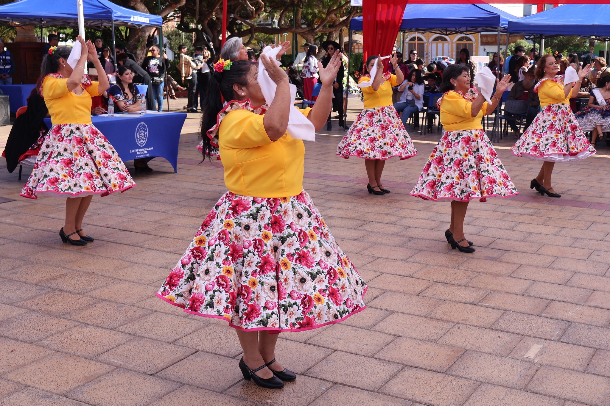 Coreografía de pañuelos de la Agrupación Danzas Doradas en la Plaza Arturo Prat; vestido amarillo y faldas florales en formación.