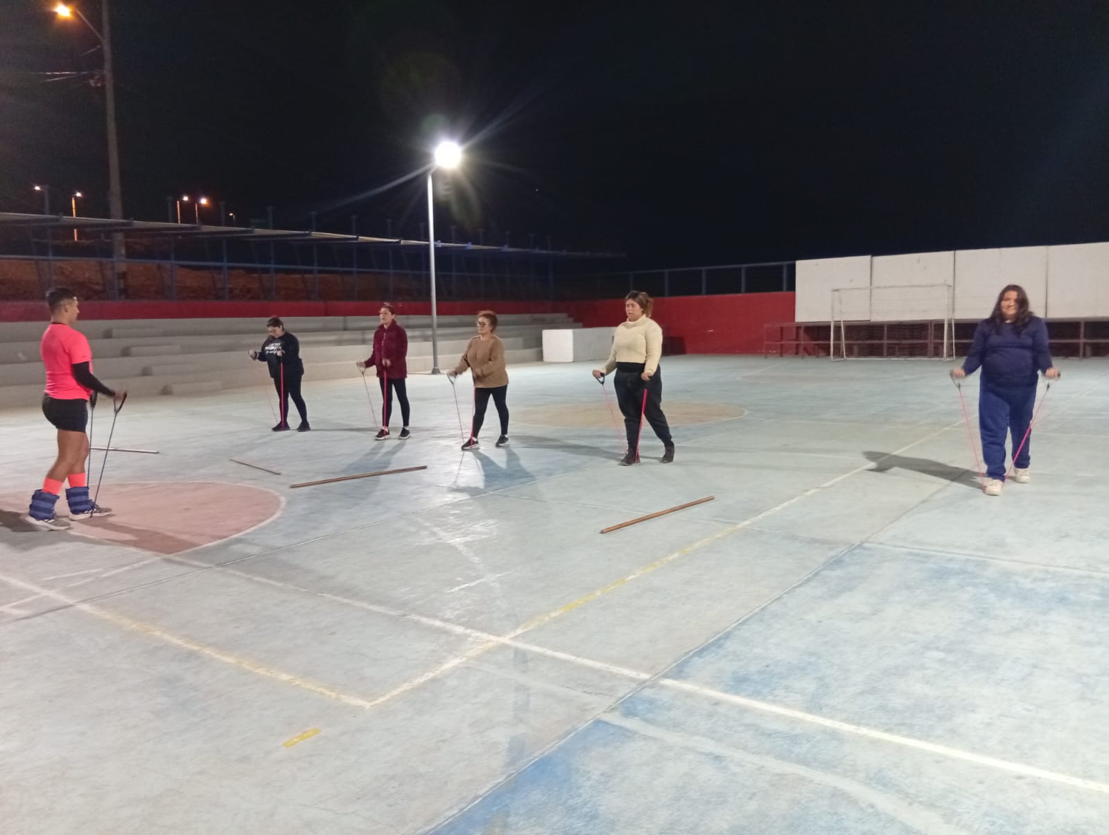 Grupo de mujeres de Paposo realiza ejercicios funcionales con palos en la multicancha.