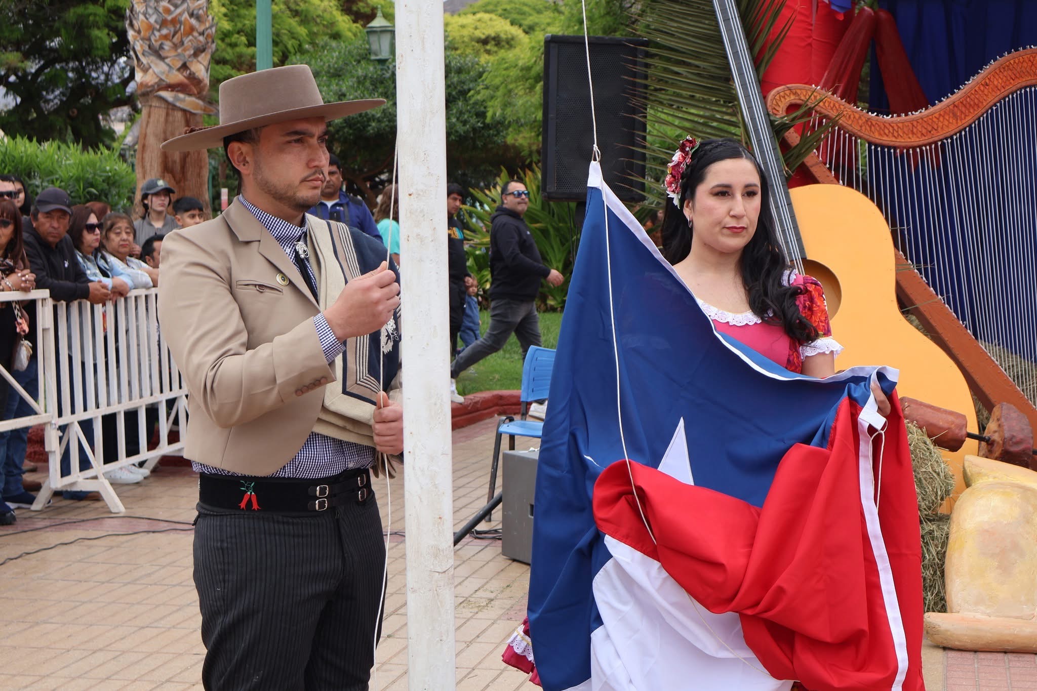 Izamiento de la bandera de Chile por pareja de profesores durante el acto de Fiestas Patrias en Taltal.