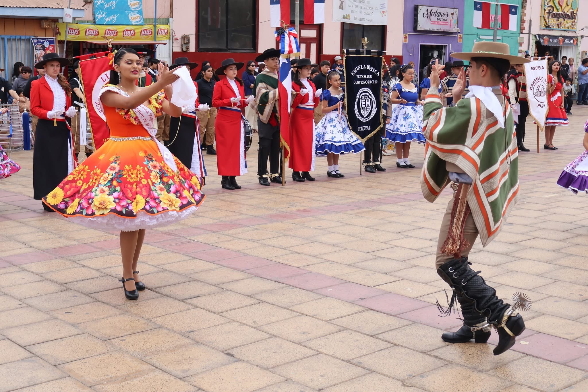 Pareja con traje típico baila cueca ante delegaciones escolares en la Plaza de Taltal.