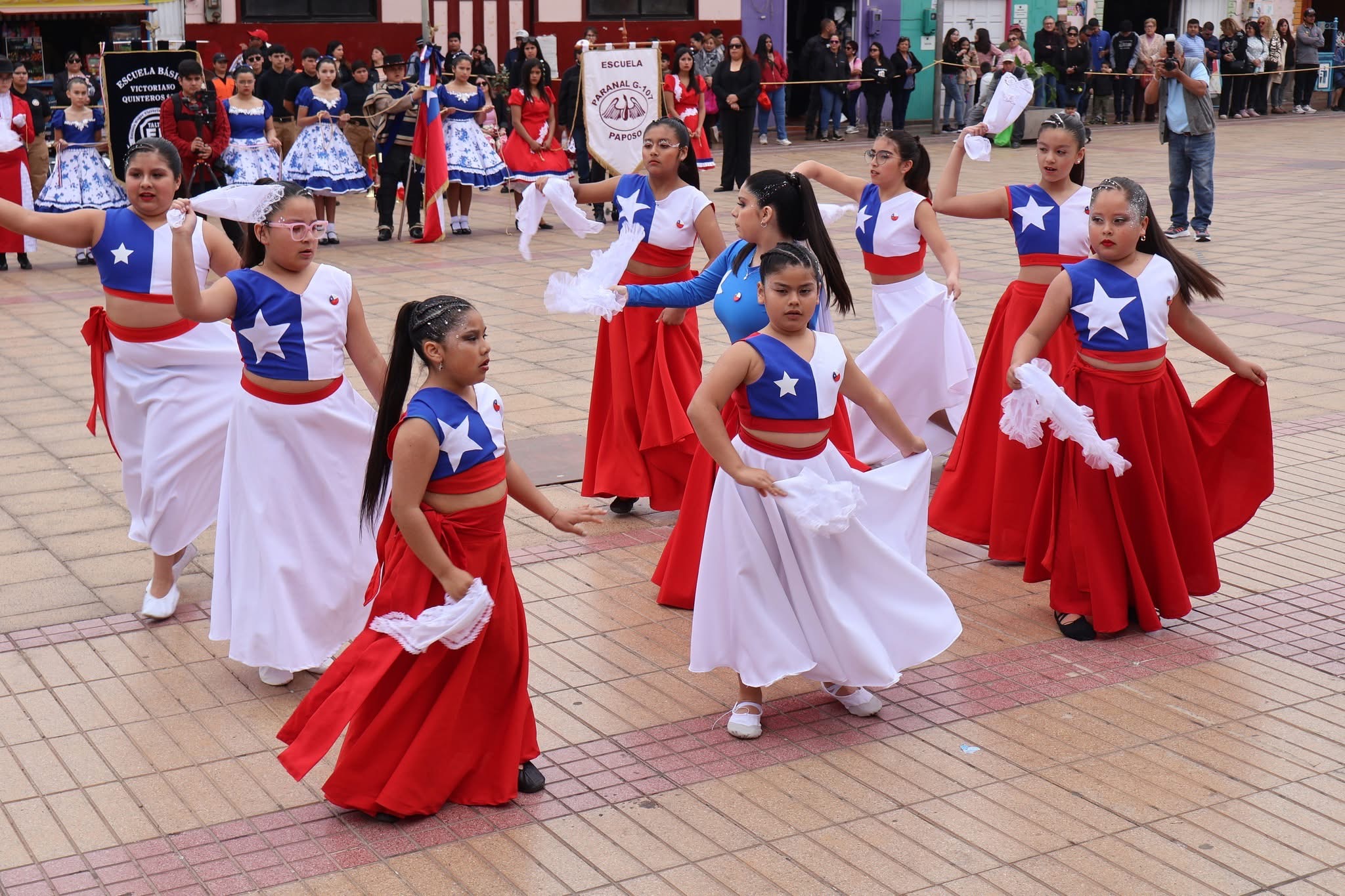 Coreografía escolar en formación con vestidos de la bandera de Chile durante el desfile.