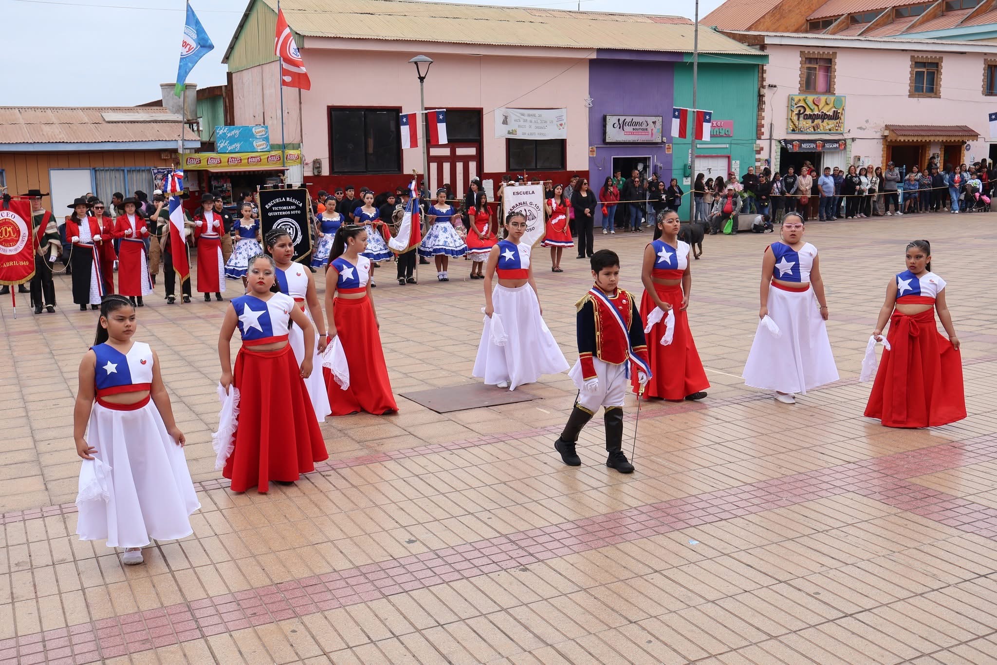 Delegación infantil en formación con alumno caracterizado de prócer abre presentación patriótica