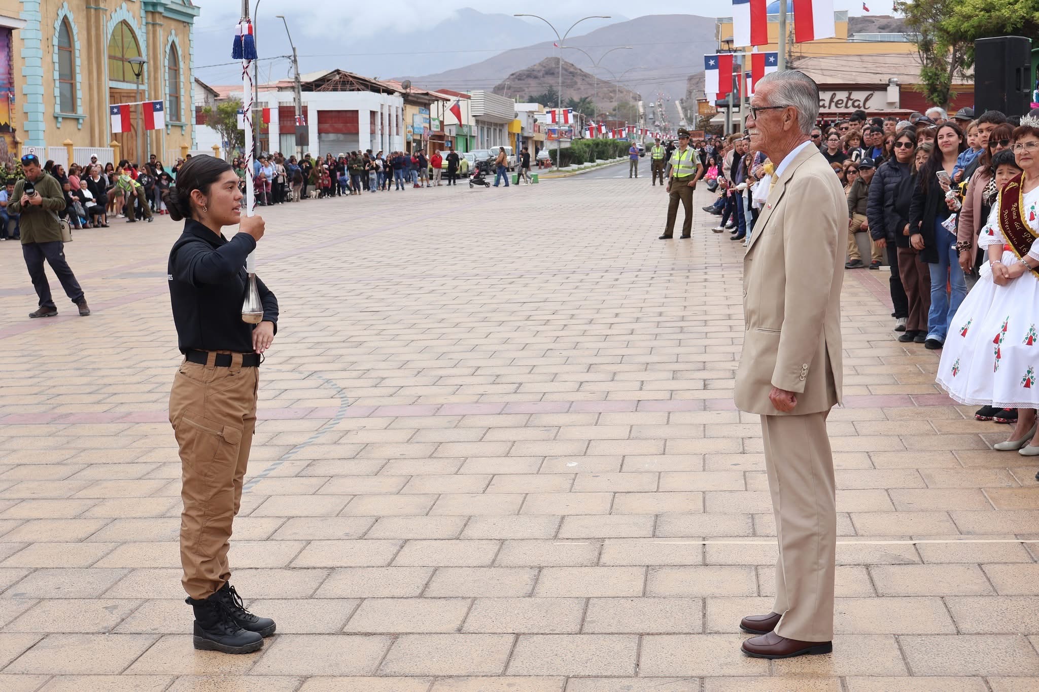 Tambor mayor rinde saludo a autoridad en medio del desfile civico-escolar.