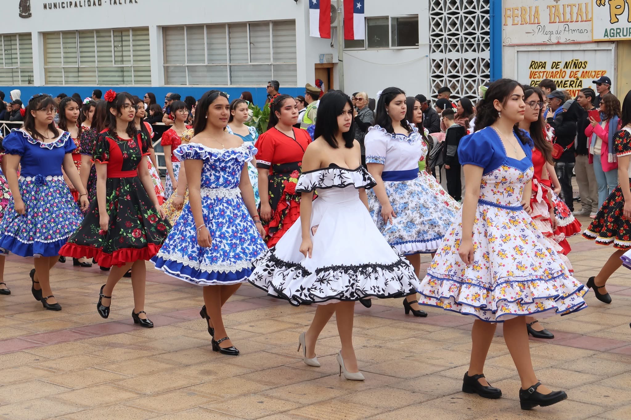 Estudiantes con coloridos vestidos de cueca marchan en filas durante el desfile cívico en Taltal.