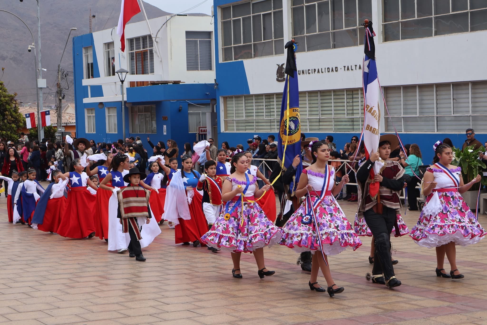 Delegaciones escolares con estandartes y banderas marchan por la avenida principal de Taltal, en el desfile de Fiestas Patrias.