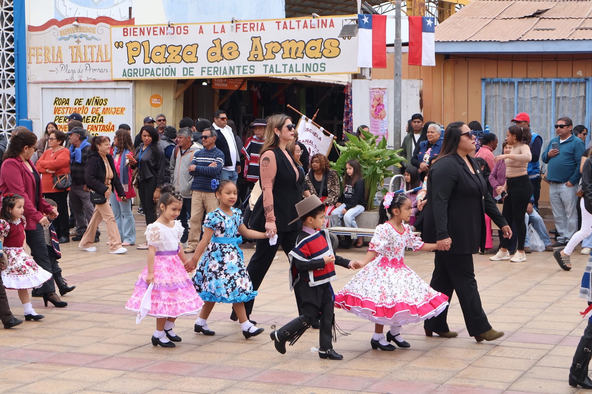 Niñas y niños con trajes típicos avanzan tomados de la mano junto a sus profesoras por la Plaza de Armas de Taltal.