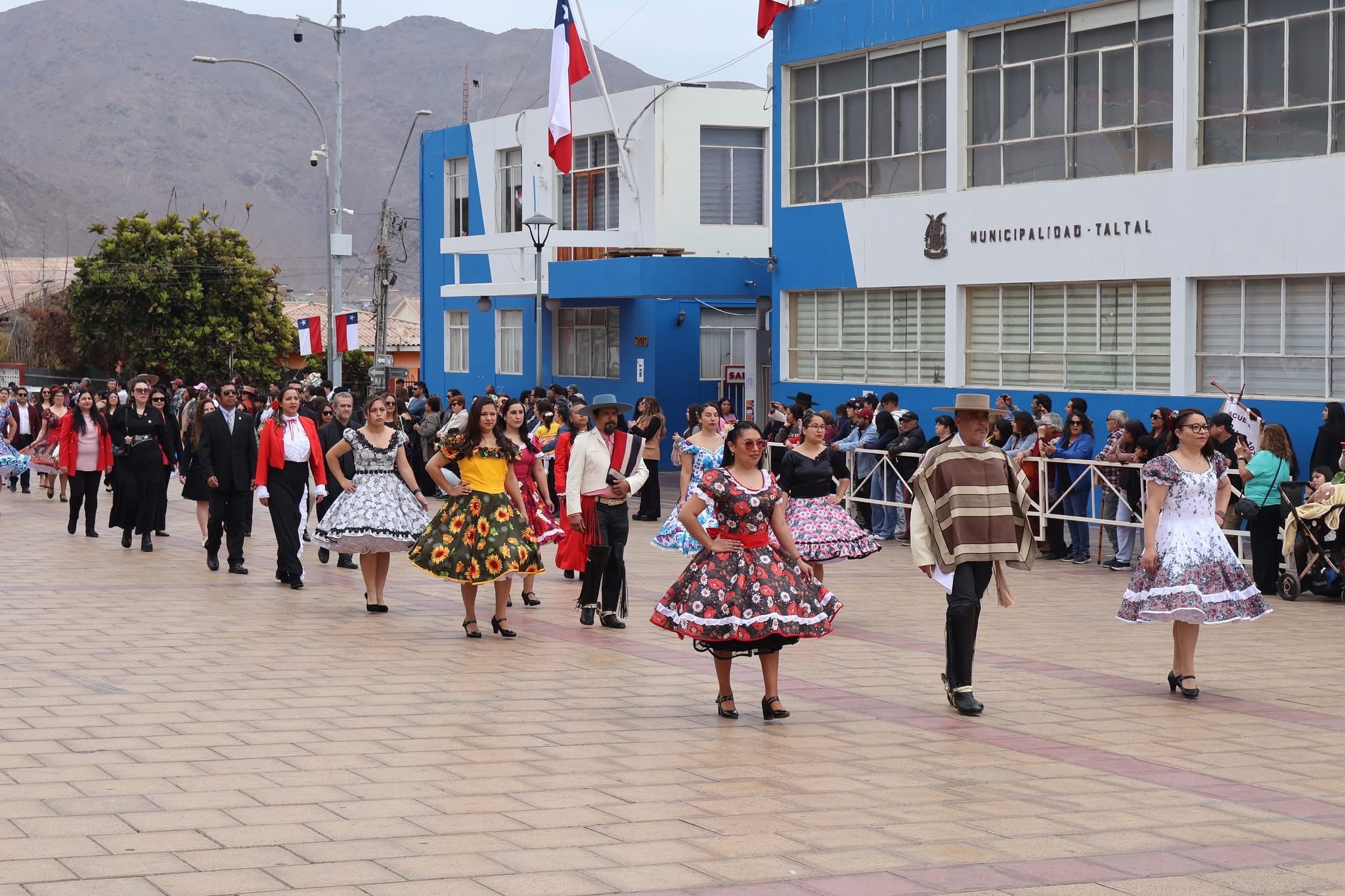 Parejas adultas con vestidos de cueca y trajes de huasos desfilan frente a la Municipalidad de Taltal durante las Fiestas Patrias.