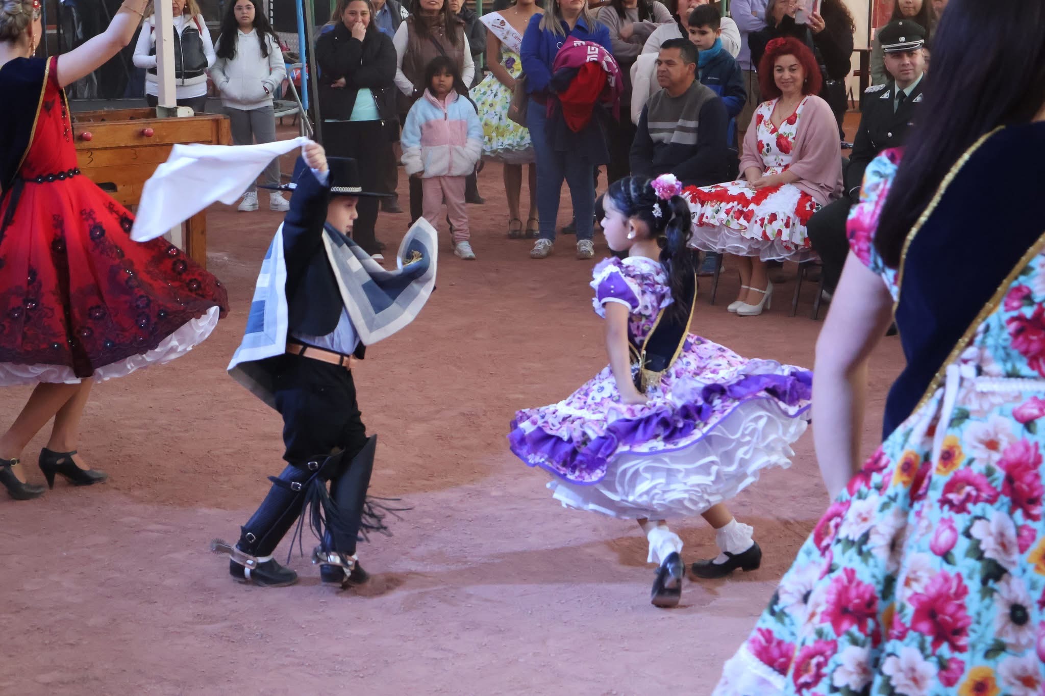 Niños en traje típico bailan cueca con pañuelos blancos durante la inauguración de las ramadas, ante la mirada de las familias.