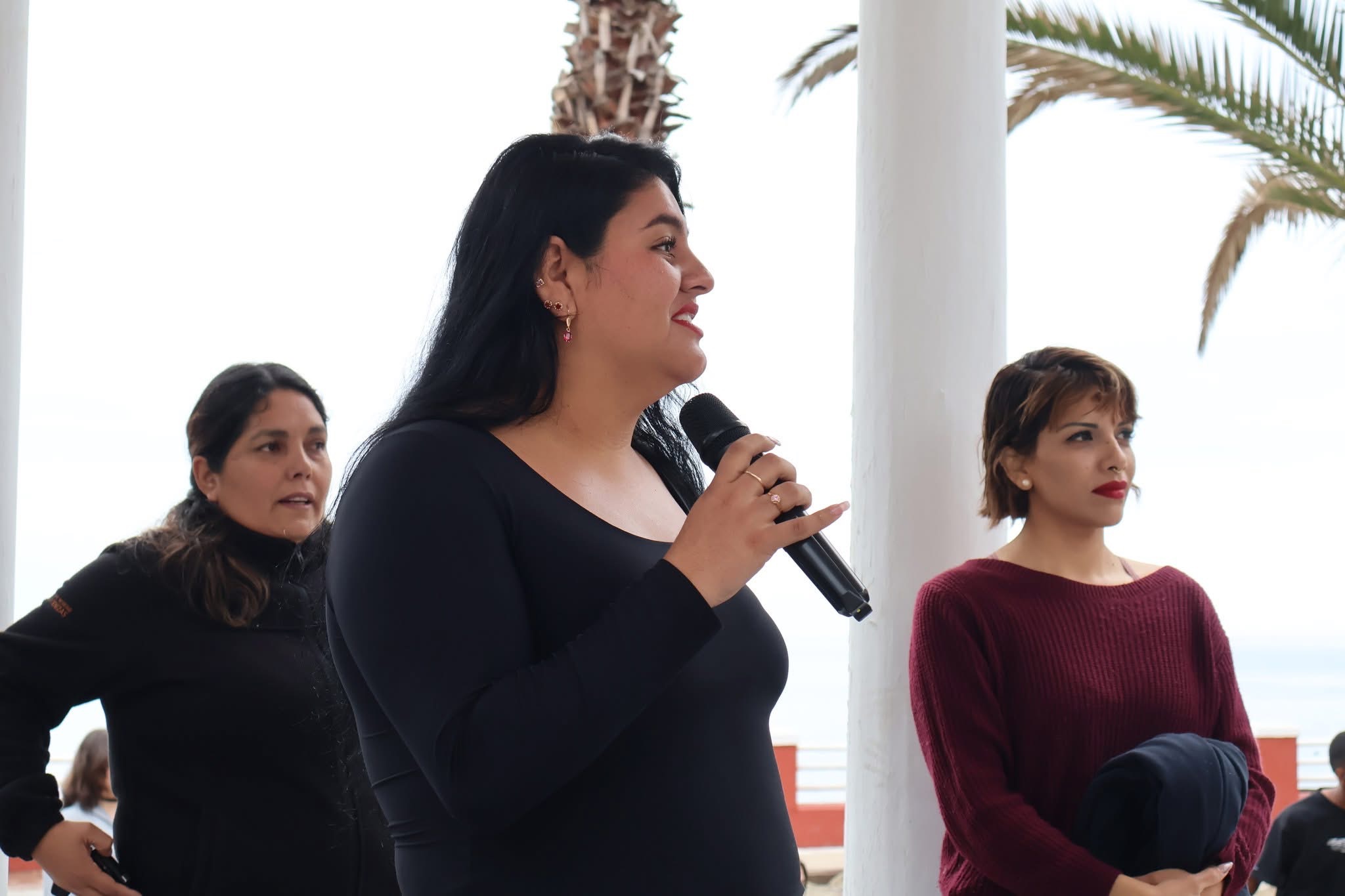Organizadora dirigiéndose a los asistentes en la plaza del muelle durante la jornada de limpieza de playas en Taltal.