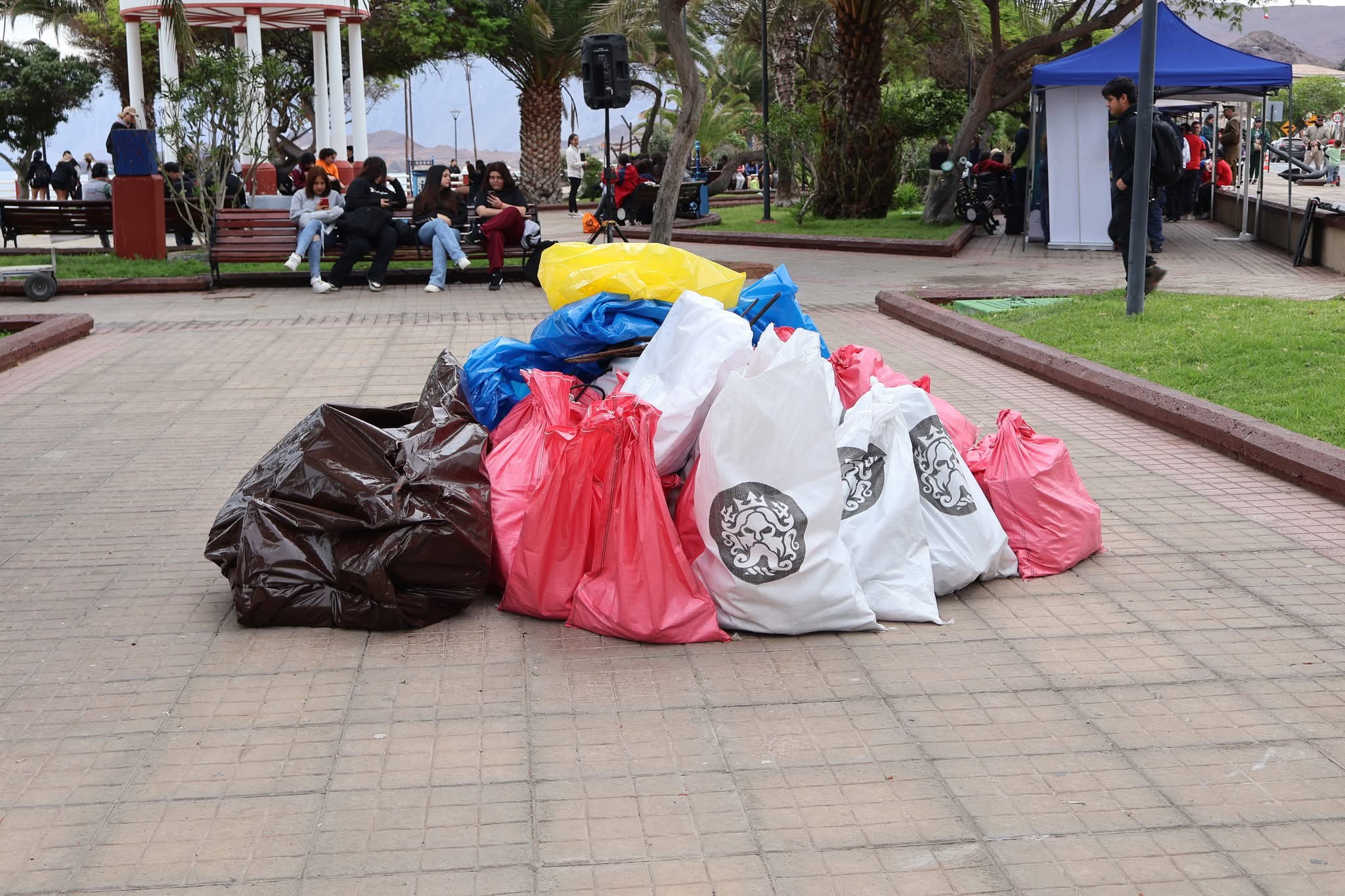 Bolsas con residuos recolectados durante la jornada de limpieza de playas en Taltal, apiladas en la plaza del muelle.