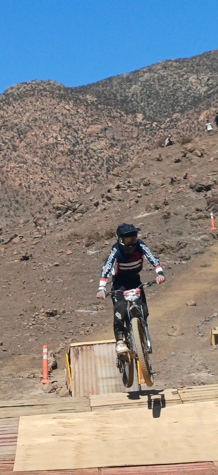 Rider taltalino realiza un salto técnico en el circuito del Downhill Zonal Norte, bajo un cielo despejado.