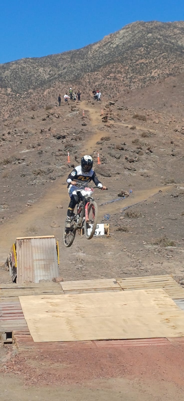 Rider taltalino realiza un salto técnico en el circuito del Downhill Zonal Norte, bajo un cielo despejado.