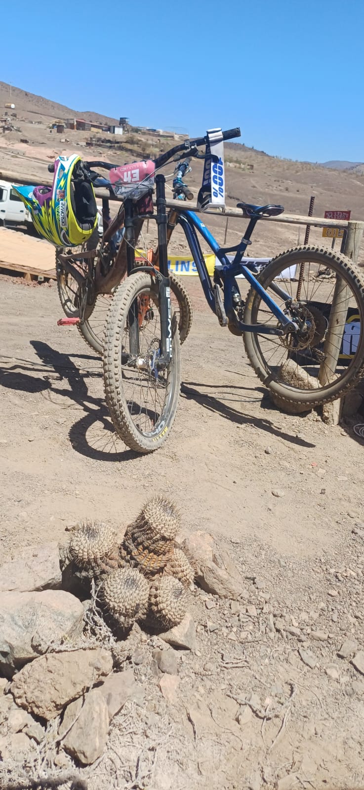 Bicicletas de Downhill apoyadas junto a un casco sobre el terreno árido del desierto taltalino.