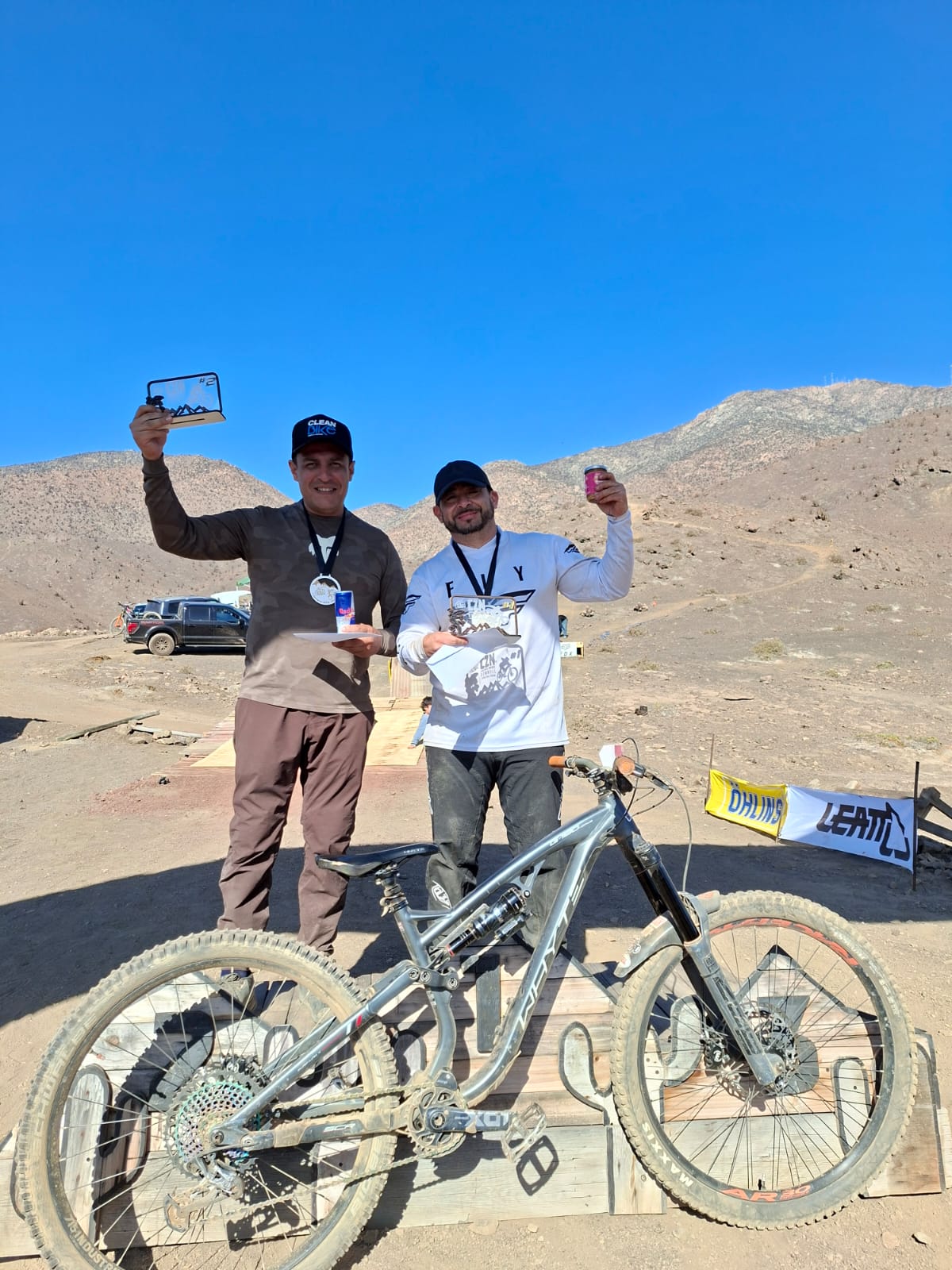 Competidores posan sonrientes en el podio del Downhill Zonal Norte con sus bicicletas tras la carrera en Taltal.