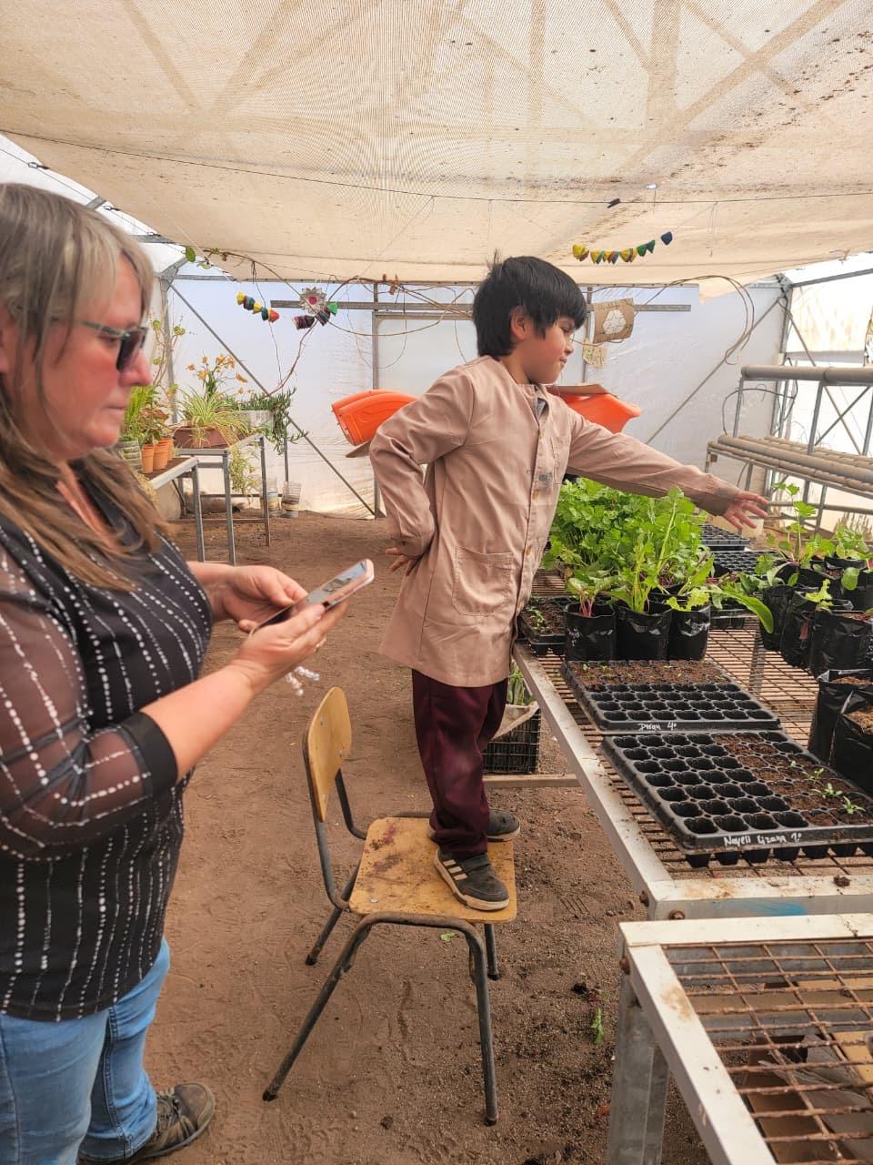 La monitora María Salazar guía a un estudiante durante la jornada práctica del Taller de Huerto Escolar en Paposo.