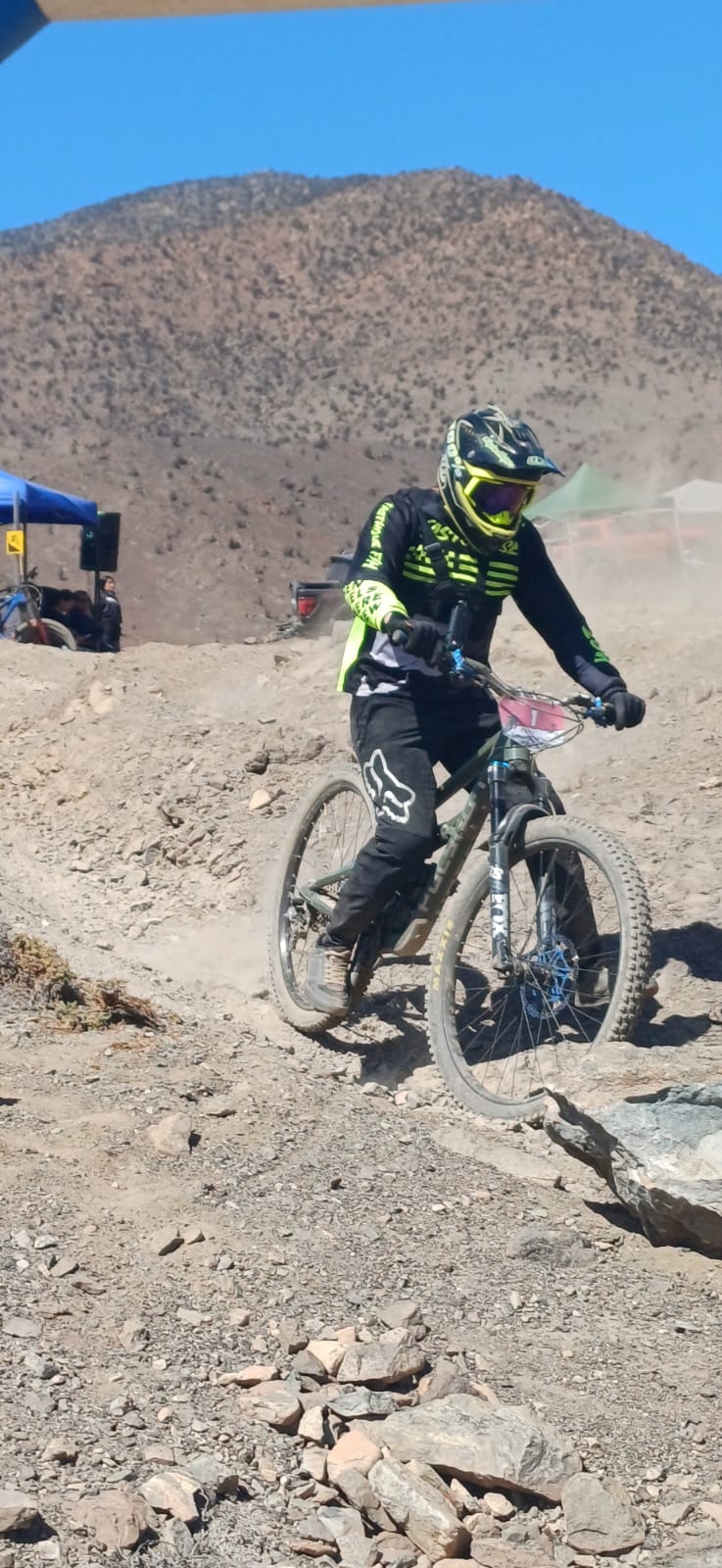 Competidor con traje negro y casco amarillo enfrenta un tramo técnico de tierra suelta en el Downhill de Taltal.