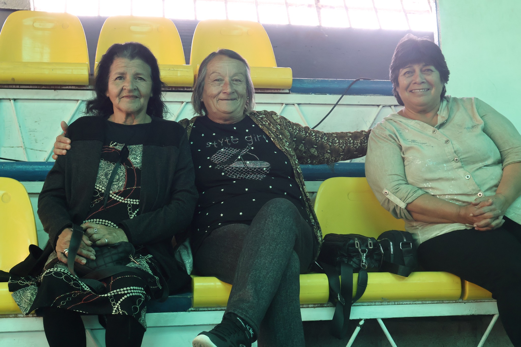 Grupo de mujeres mayores sonrientes disfrutando de la jornada de celebración en el Estadio Techado Municipal.