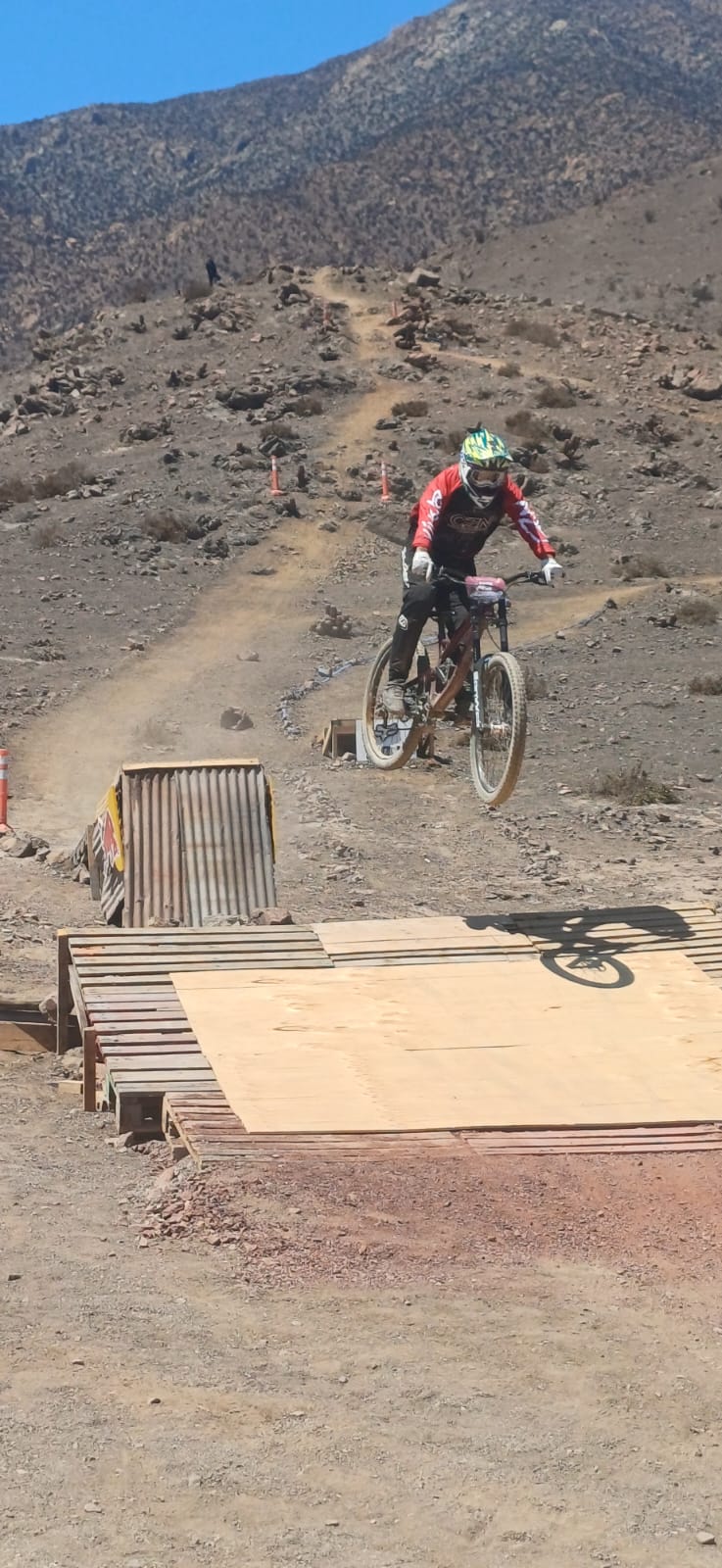 Ciclista en pleno salto sobre rampa de madera en la pista de Downhill de Taltal.