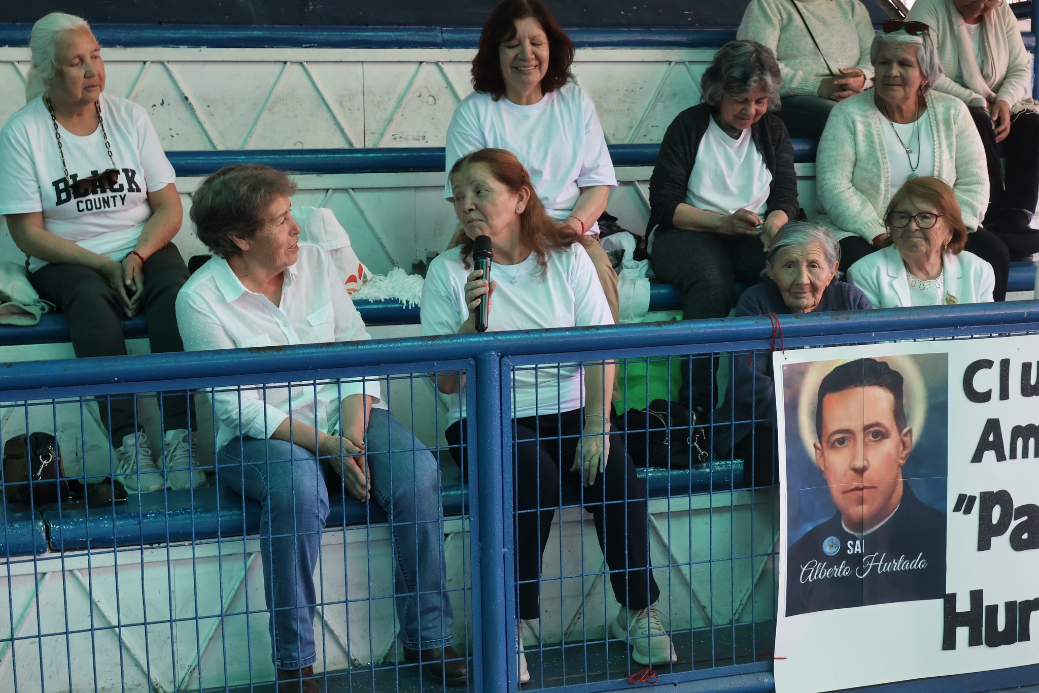 Integrantes del Club de Amigos Padre Hurtado compartiendo en las graderías del gimnasio durante el evento.