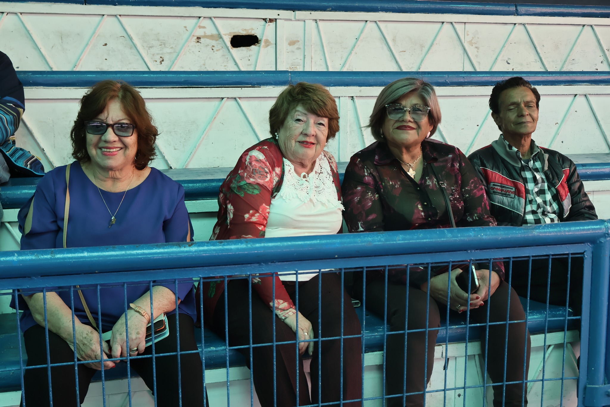Primer plano de asistentes mayores sonriendo en las graderías durante la celebración del Mes del Adulto Mayor en Taltal.
