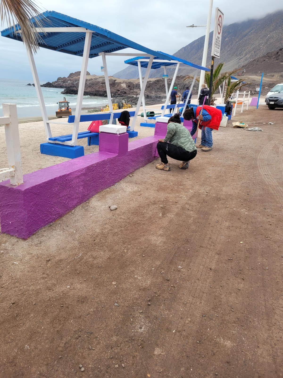 Reacondicionamiento y pintura de bancas y quitasoles frente al mar.