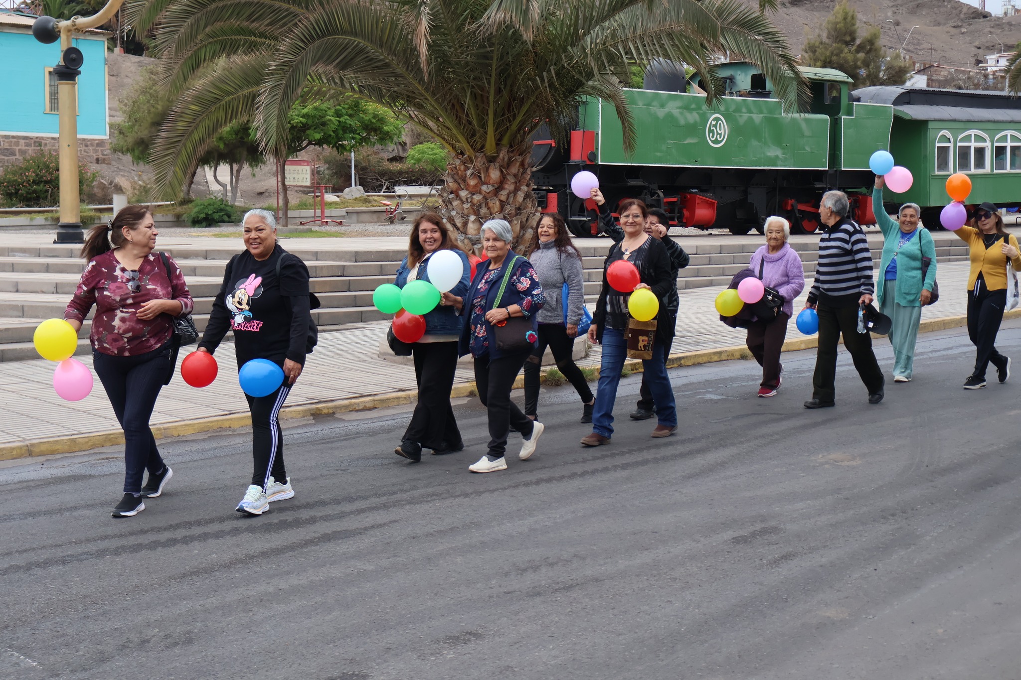 Mujeres adultas mayores enérgicas marchando con globos de colores en una celebración comunitaria.