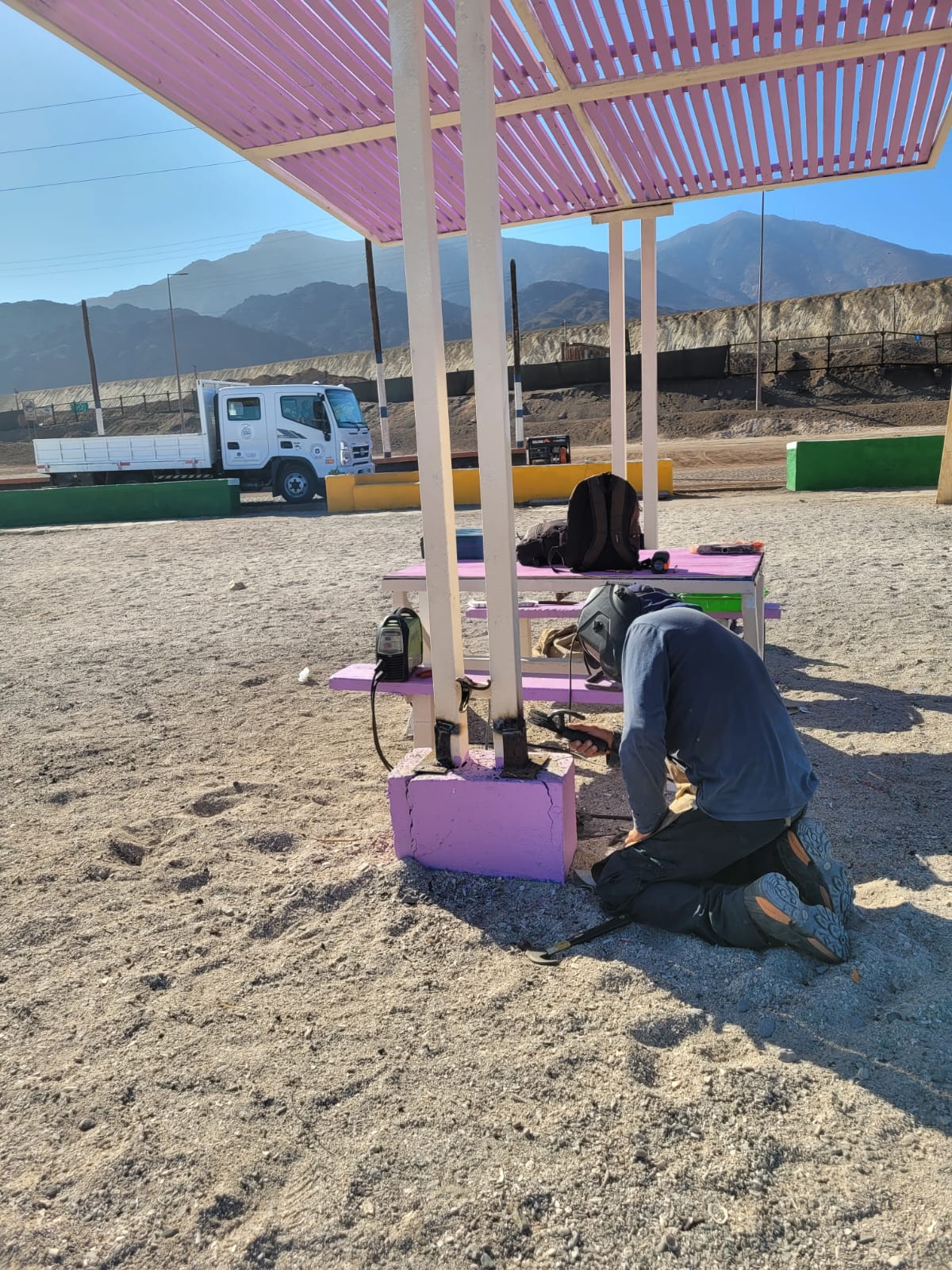 Operarios reacondicionan áreas de descanso bajo quitasoles de colores.