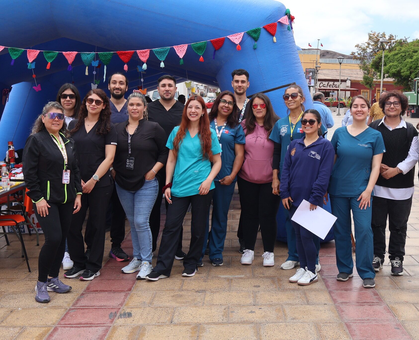 Personal joven de salud y staff organizador posando en grupo con la bandera chilena al fondo.