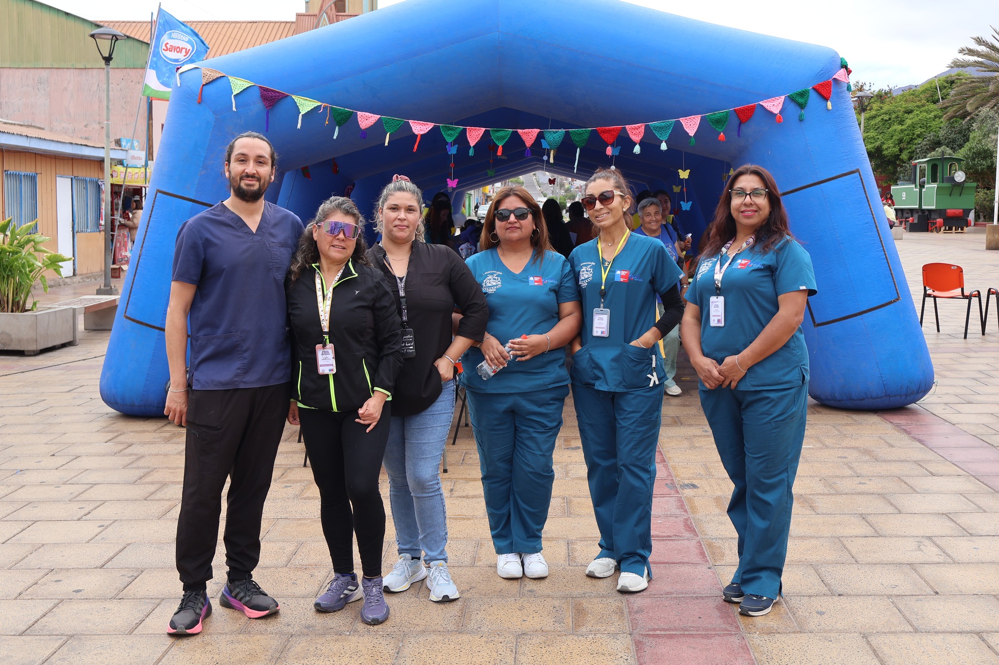 Grupo de personal de salud o staff organizador posando frente a la carpa inflable azul.