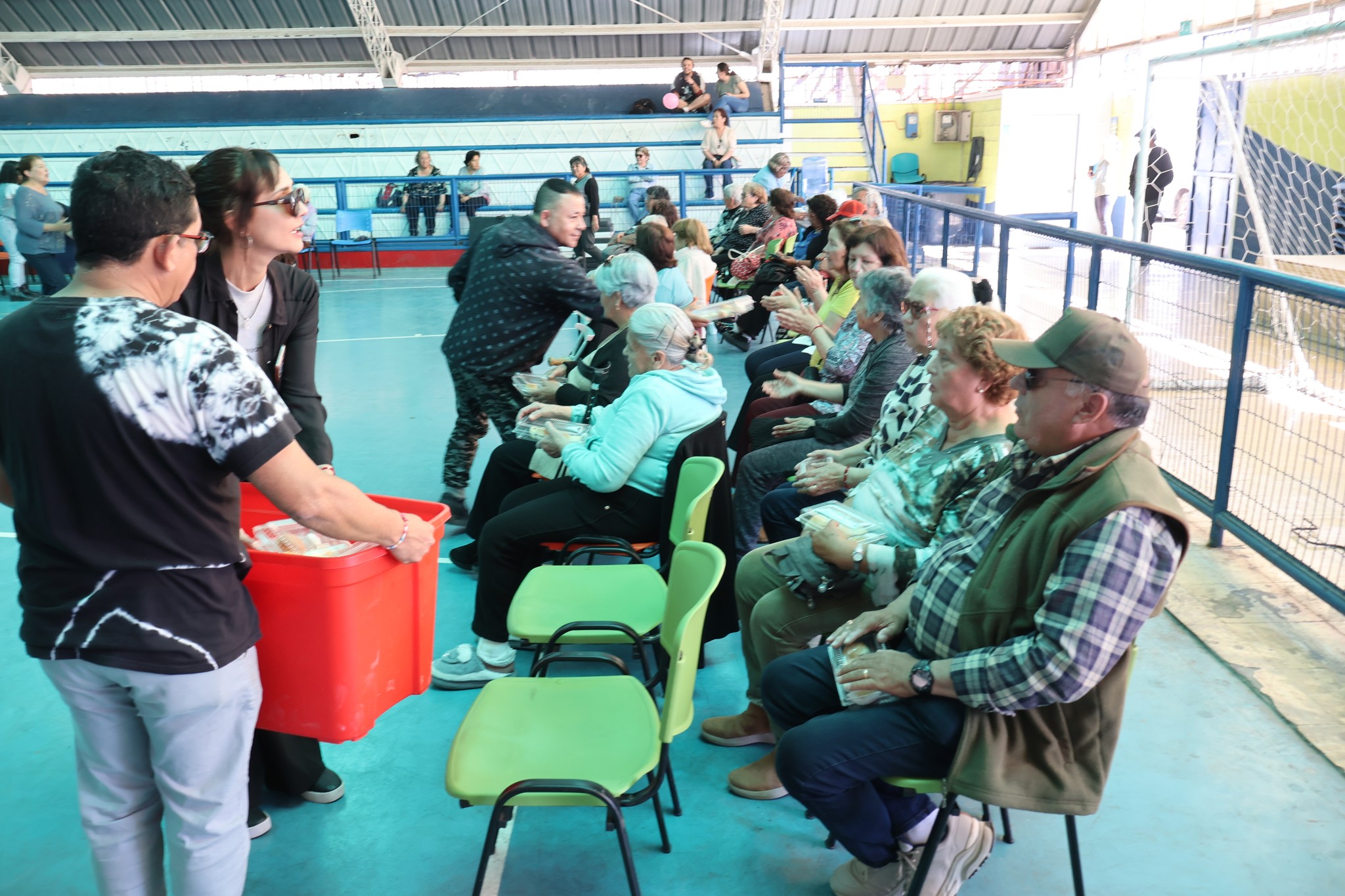 Equipo municipal de Taltal entrega colaciones a los adultos mayores durante la jornada recreativa en el Estadio Techado.